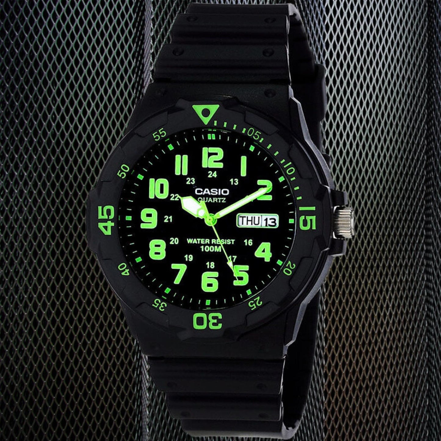 Casio MRW200H-3BV dive style sport watch with black dial, glowing green numerals, rotating bezel and black resin strap in dark studio setting.