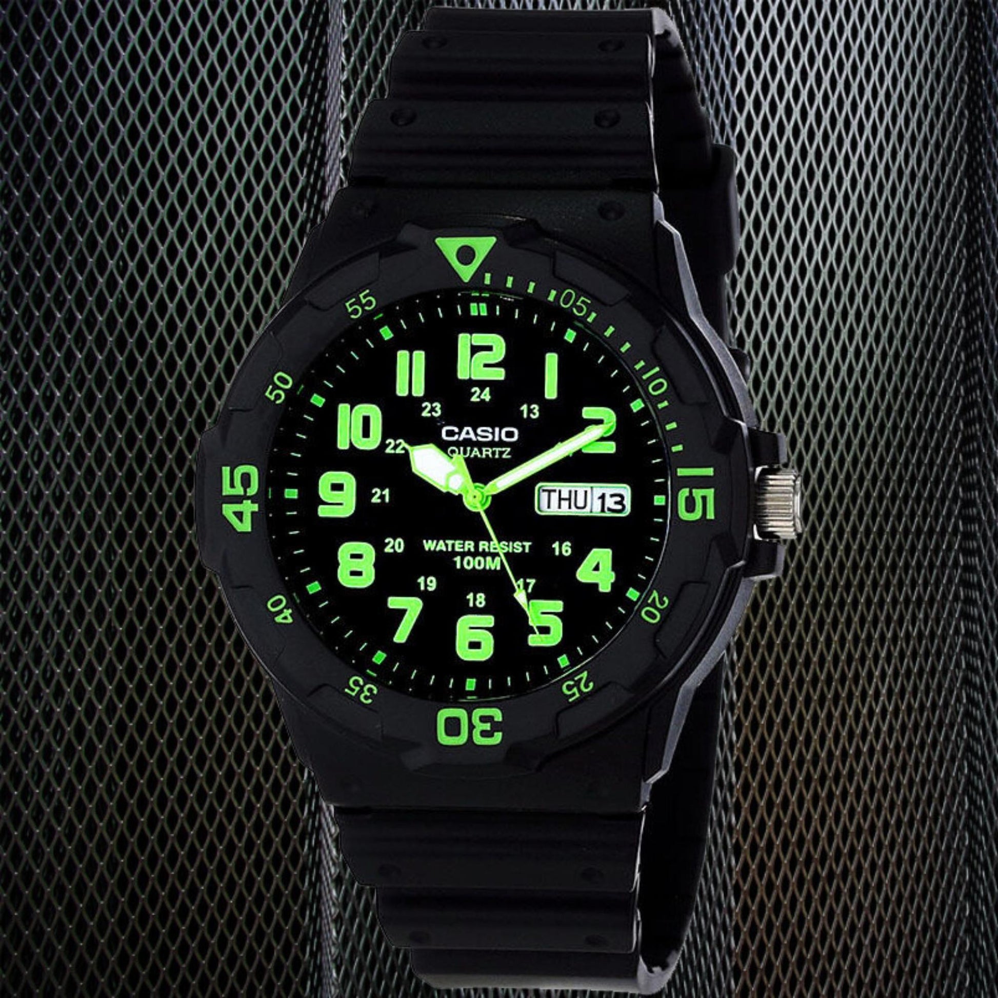Casio MRW200H-3BV dive style sport watch with black dial, glowing green numerals, rotating bezel and black resin strap in dark studio setting.