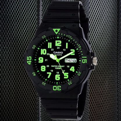 Casio MRW200H-3BV dive style sport watch with black dial, glowing green numerals, rotating bezel and black resin strap in dark studio setting.