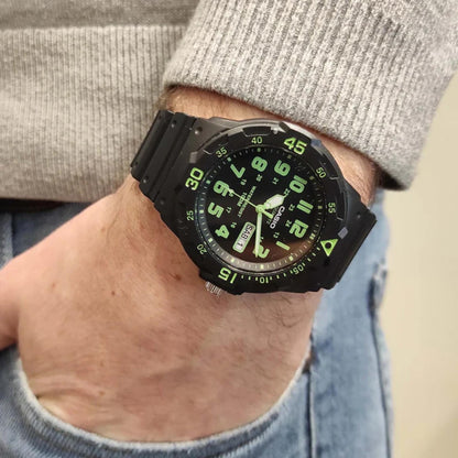Casio MRW200H-3BV dive style sport watch worn on wrist with black dial, green numerals, rotating bezel and black resin strap.