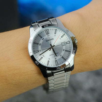 Reloj Casio MTP-V004D-7CUDF en muñeca con esfera plateada efecto sol, fecha a las 3 y brazalete de acero inoxidable.
