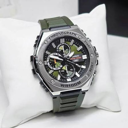 Casio MWA-300H-3A chronograph watch with a green dial, silver-tone bezel, bold hour markers, and dark green strap displayed on a watch cushion.
