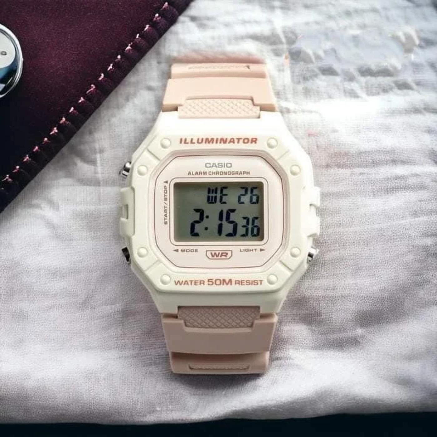 Reloj Casio W218HC-4A2V digital en tonos beige y rosa apoyado sobre tela clara, con pantalla LCD y resistencia al agua 50M.