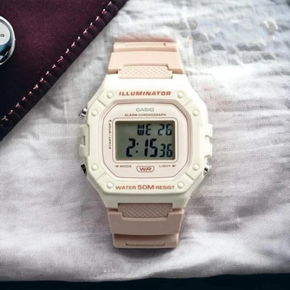 Reloj Casio W218HC-4A2V digital en tonos beige y rosa apoyado sobre tela clara, con pantalla LCD y resistencia al agua 50M.