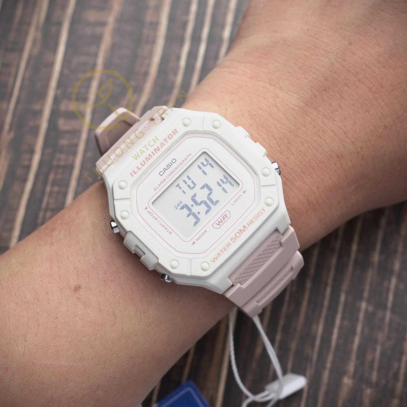 Reloj Casio W218HC-4A2V digital en tonos rosa y beige colocado en la muñeca, con pantalla LCD y resistencia al agua 50M.