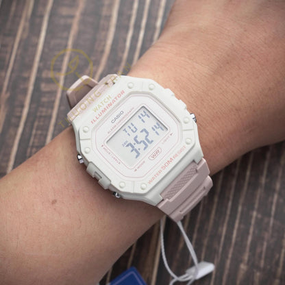 Reloj Casio W218HC-4A2V digital en tonos rosa y beige colocado en la muñeca, con pantalla LCD y resistencia al agua 50M.