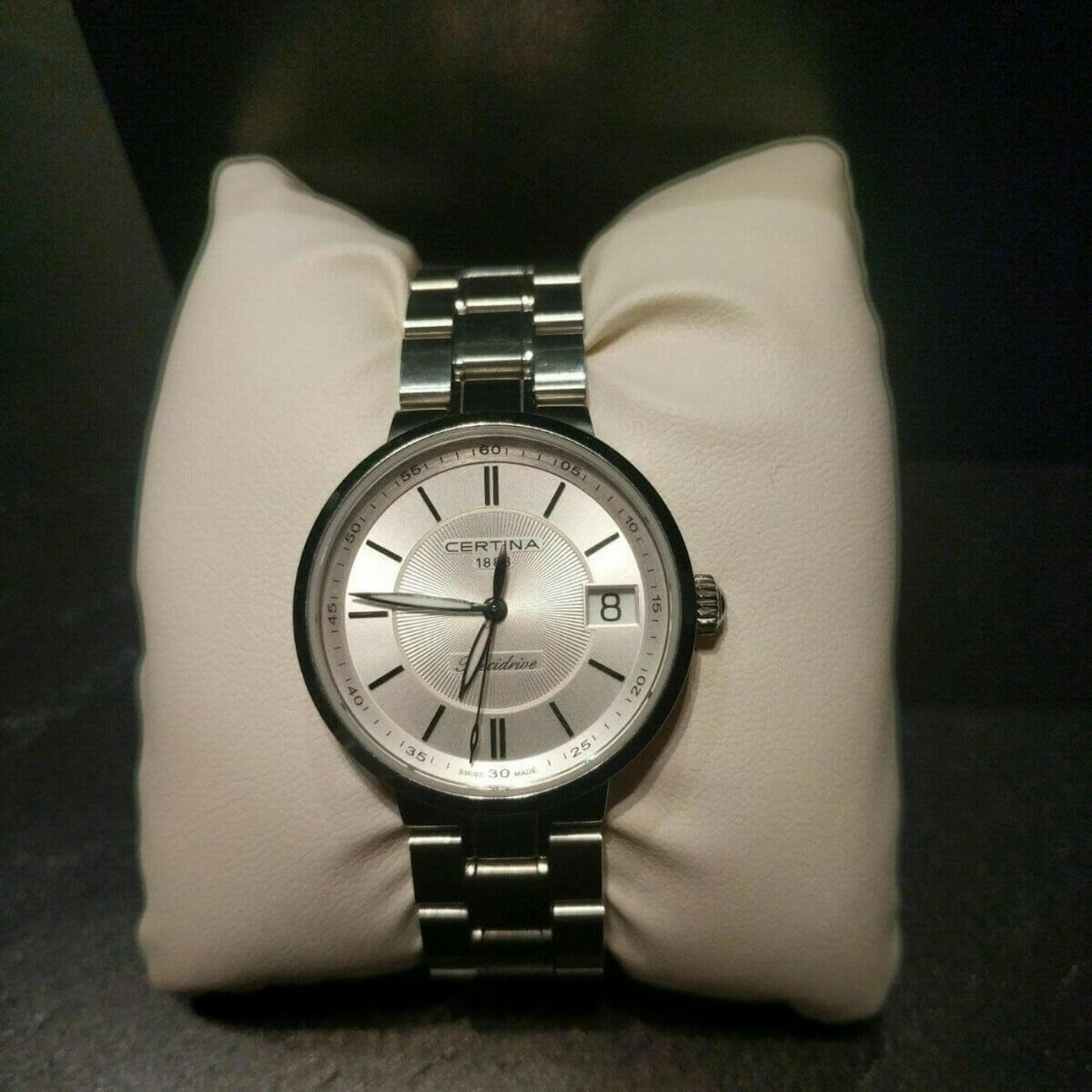 Reloj Certina C031.210.44.113.00 con esfera plateada y brazalete de titanio, presentado sobre cojín.