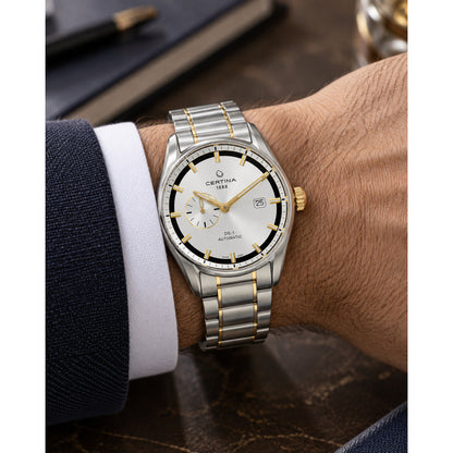 Certina DS-1 automatic men's watch worn on the wrist featuring a silver dial, gold-tone accents, and a two-tone stainless steel bracelet.