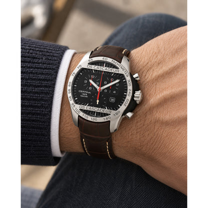 Certina DS Cascadeur quartz chronograph watch worn on a man's wrist, highlighting the black dial and brown leather strap.