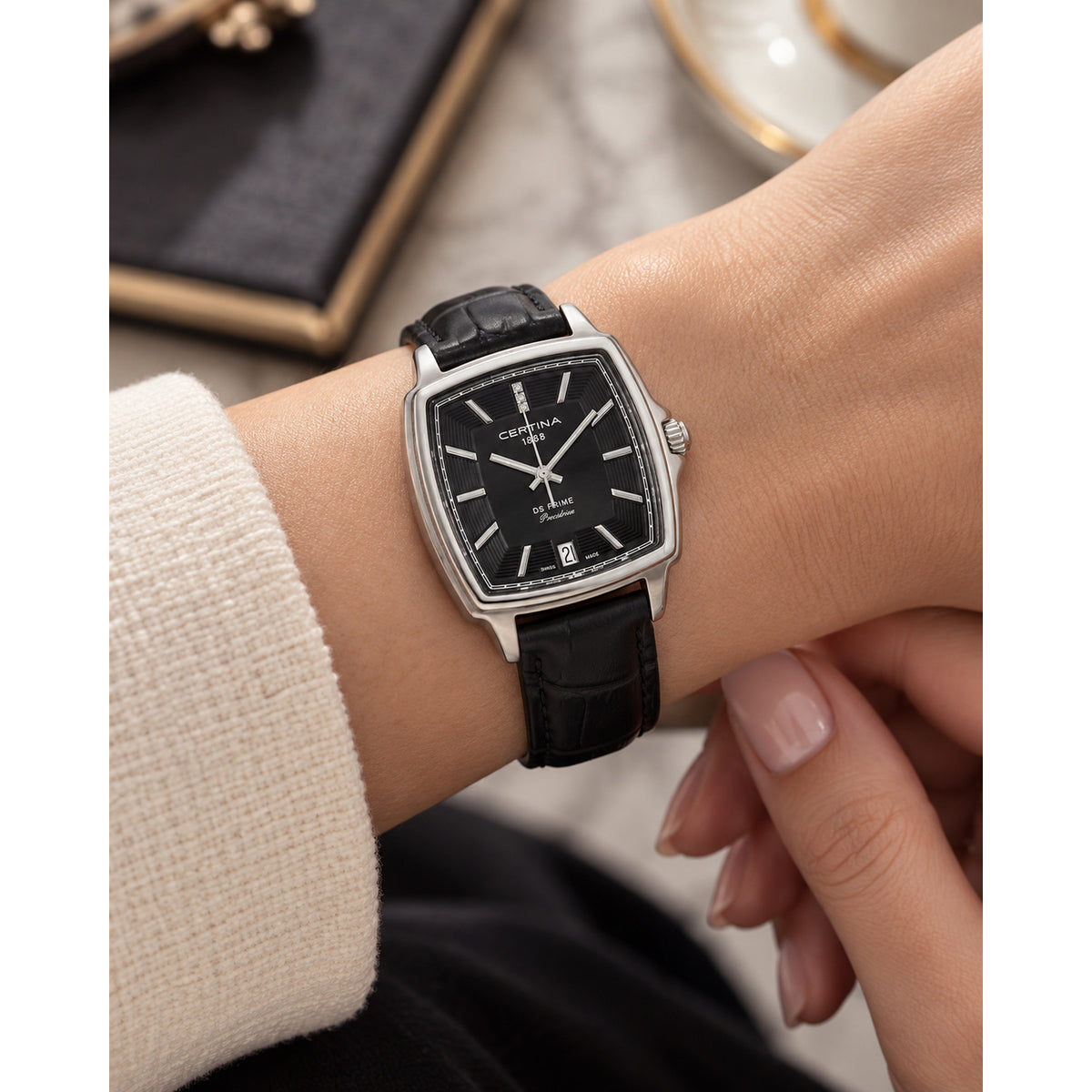 Certina DS Prime women's quartz watch worn on the wrist, displaying the black dial and black leather strap.