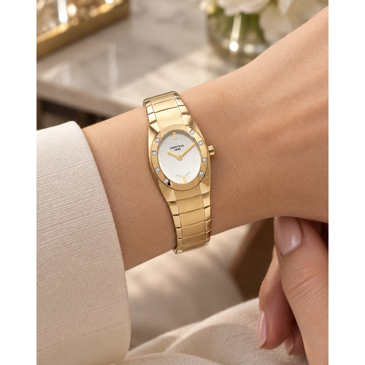 Certina DS Spel Mini Lady quartz watch worn on wrist with gold-tone stainless steel bracelet and white dial