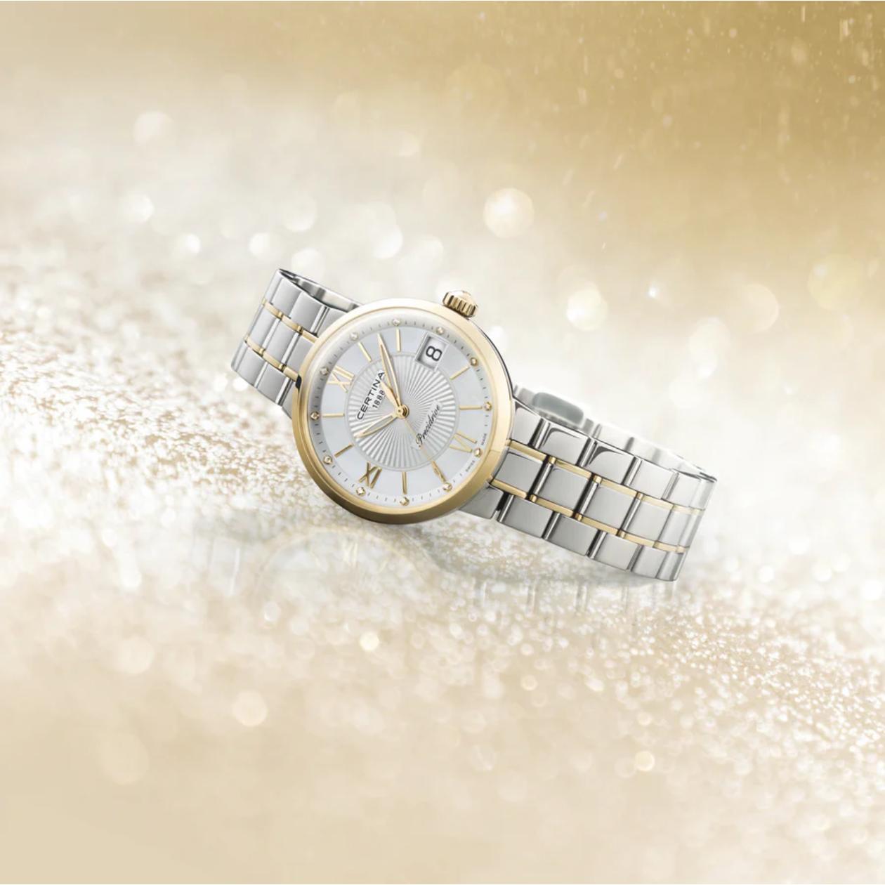 Certina DS Stella C031.210.22.116.00 en escena ambientada con fondo dorado brillante, reloj bicolor en acero y dorado con esfera de nácar, diamantes como índices y fecha a las 3.