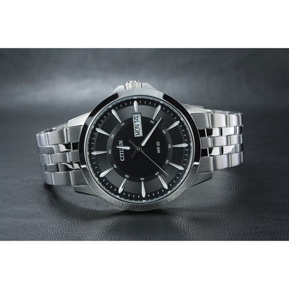 Reloj Citizen BF2011-51E con esfera negra y brazalete de acero inoxidable, presentado sobre fondo oscuro.