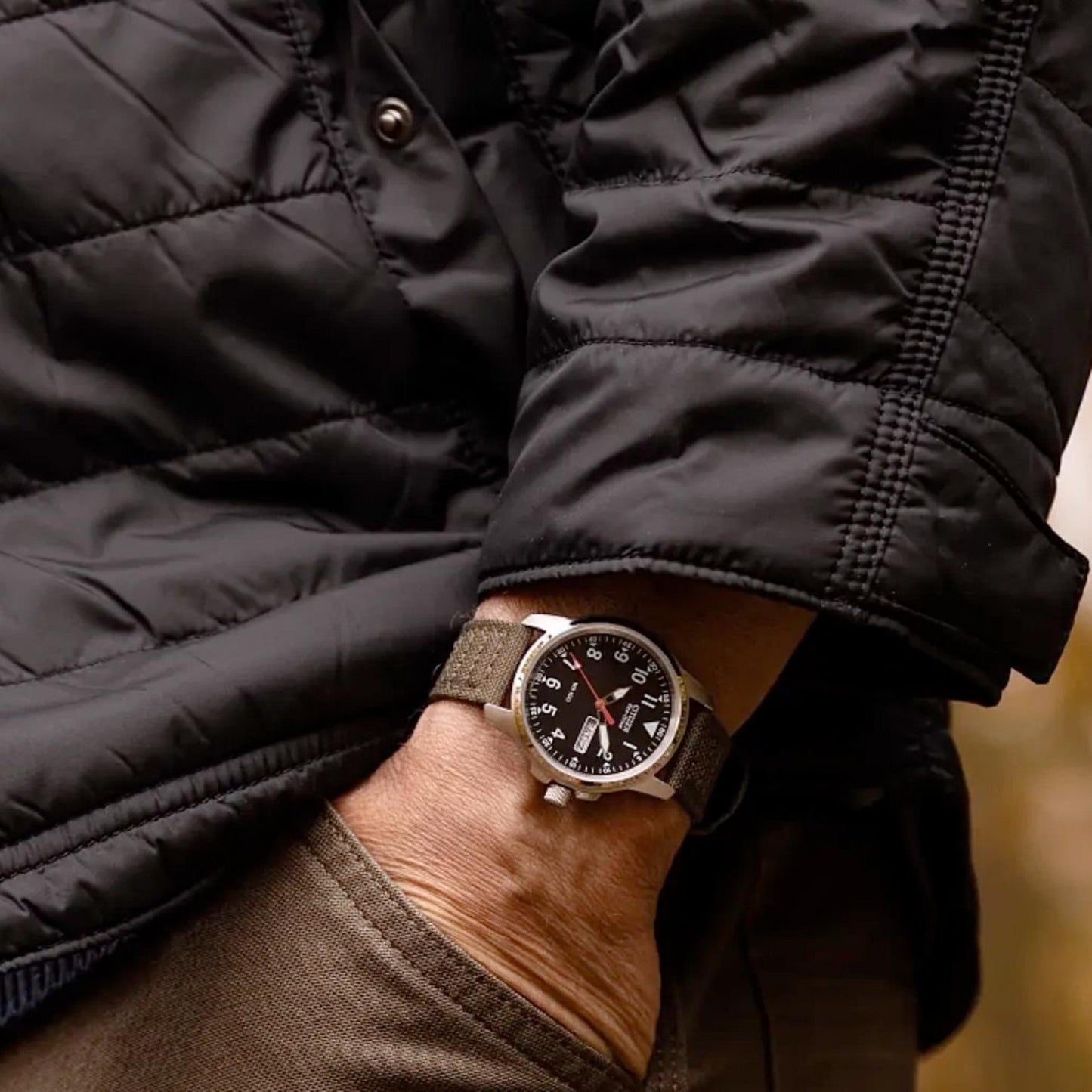 Citizen BM8180-03E worn on the wrist with black dial, white Arabic numerals, day-date display, stainless steel case, and green nylon strap.