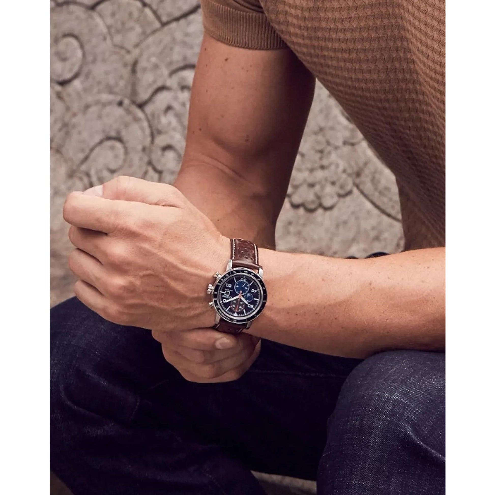 Citizen CA0648-09L Eco-Drive chronograph worn on the wrist with blue dial, tachymeter bezel, stainless steel case and brown perforated leather strap.
