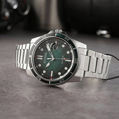 Reloj Citizen Eco-Drive de acero con esfera verde colocado en posición inclinada sobre superficie oscura de estilo urbano.