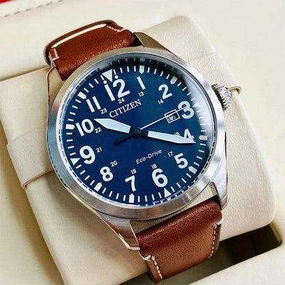 Citizen Eco Drive field watch close up with blue dial, arabic numerals, date window and brown leather strap on display cushion
