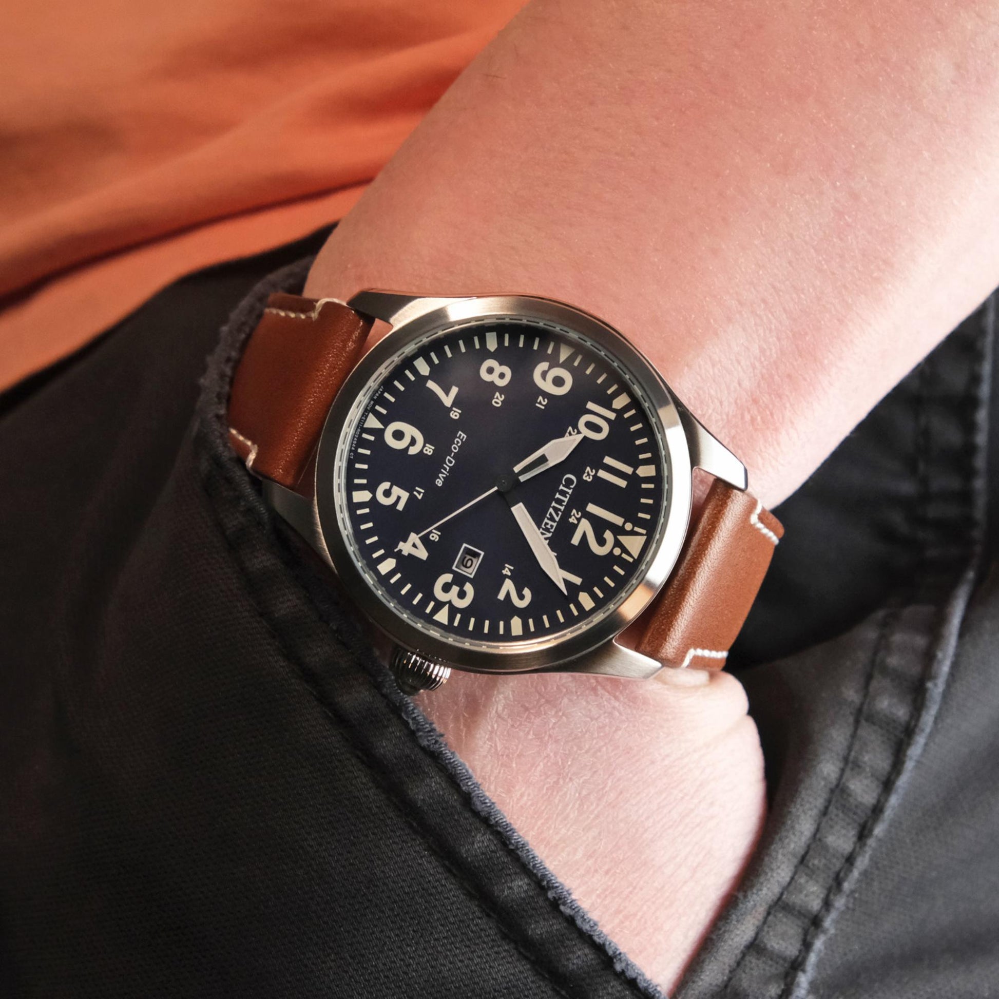 Citizen Eco Drive mens field watch with black dial and arabic numerals worn on wrist with brown leather strap in casual outdoor style