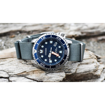 Citizen Eco-Drive Promaster Diver BN0151-09L with blue dial, blue rotating bezel, luminous hour markers, date window, stainless steel case, and gray fabric strap resting on a weathered wood surface.