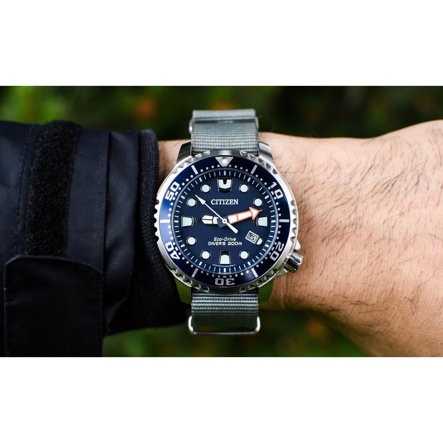 Citizen Eco-Drive Promaster Diver BN0151-09L worn on the wrist with blue dial, blue rotating bezel, luminous hour markers, date window, stainless steel case, and gray fabric strap.