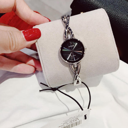 Citizen EX1420-50E Eco-Drive watch with black dial and polished stainless steel bangle bracelet placed on display cushion with twisted design links