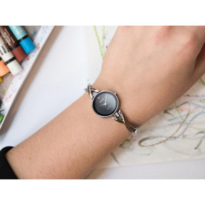 Citizen EX1420-50E Eco-Drive watch worn on wrist with black dial, minimalist design and polished stainless steel bangle bracelet with twisted links