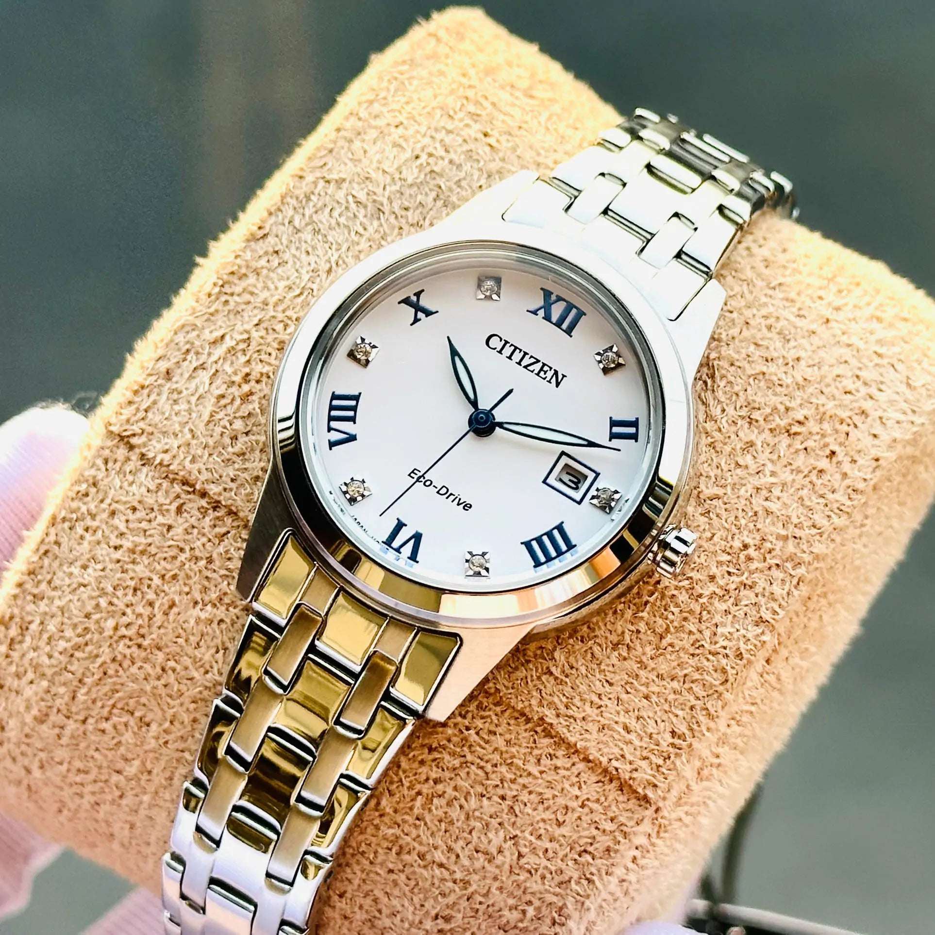 Citizen FE1240-57A Eco-Drive with white dial, blue Roman numerals, date window and stainless steel case and bracelet shown in close-up.