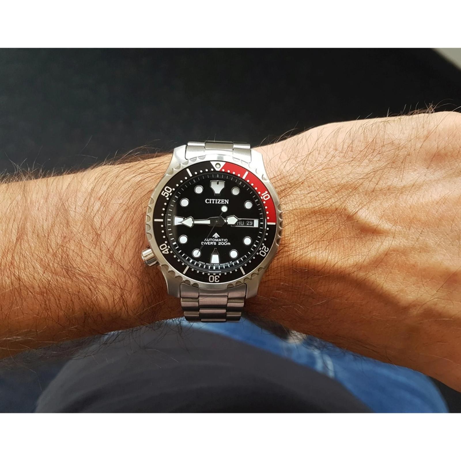 Citizen NY0085-86E automatic dive watch worn on the wrist with black dial, red and black rotating bezel, stainless steel case and stainless steel bracelet.