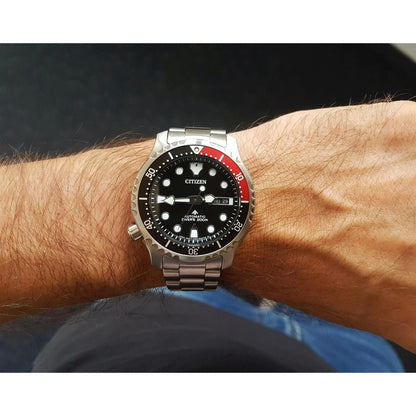 Citizen NY0085-86E automatic dive watch worn on the wrist with black dial, red and black rotating bezel, stainless steel case and stainless steel bracelet.