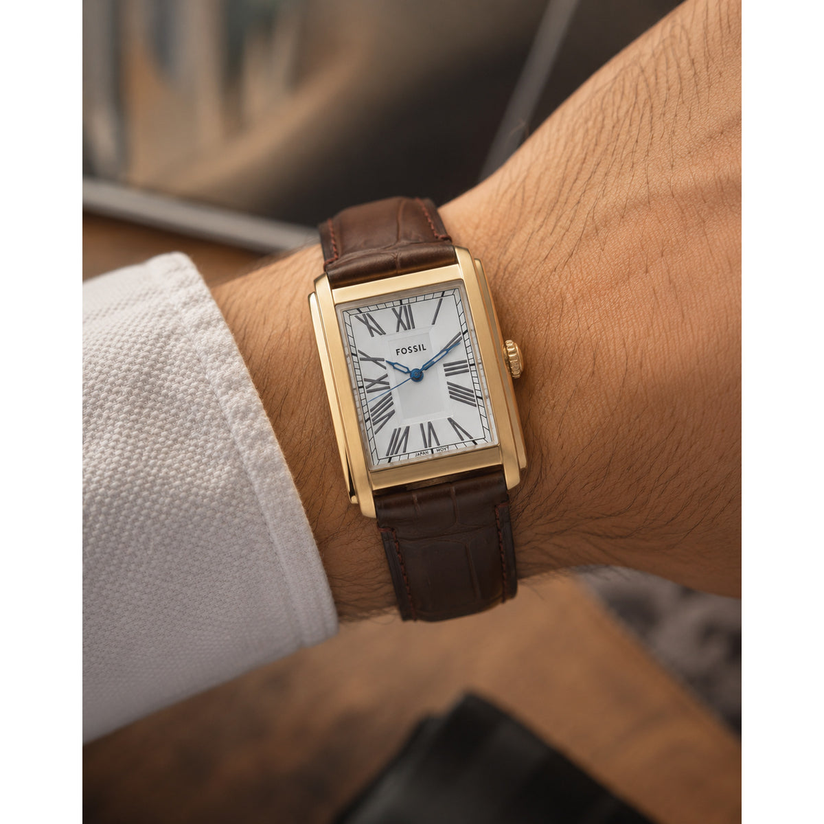 Fossil Carraway FS6011 with a silver dial, Roman numeral hour markers, blue hands, rectangular gold-tone case, and brown leather strap worn on the wrist.