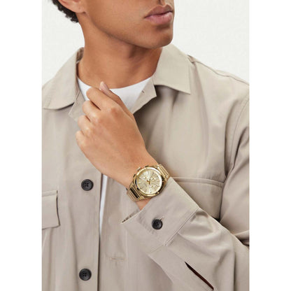 Fossil FS6119 mens chronograph watch with champagne dial and gold tone bracelet worn on wrist in smart elegant outfit