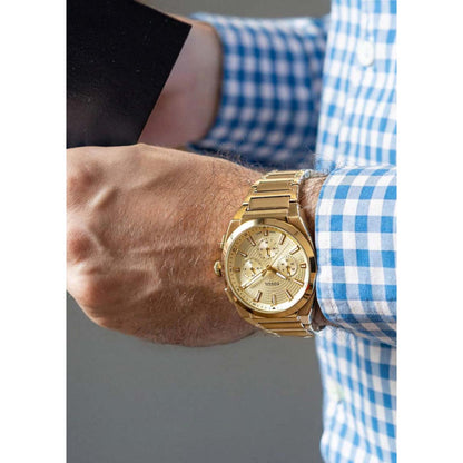 Fossil FS6119 mens chronograph watch with champagne dial and gold tone bracelet worn on wrist in smart casual style