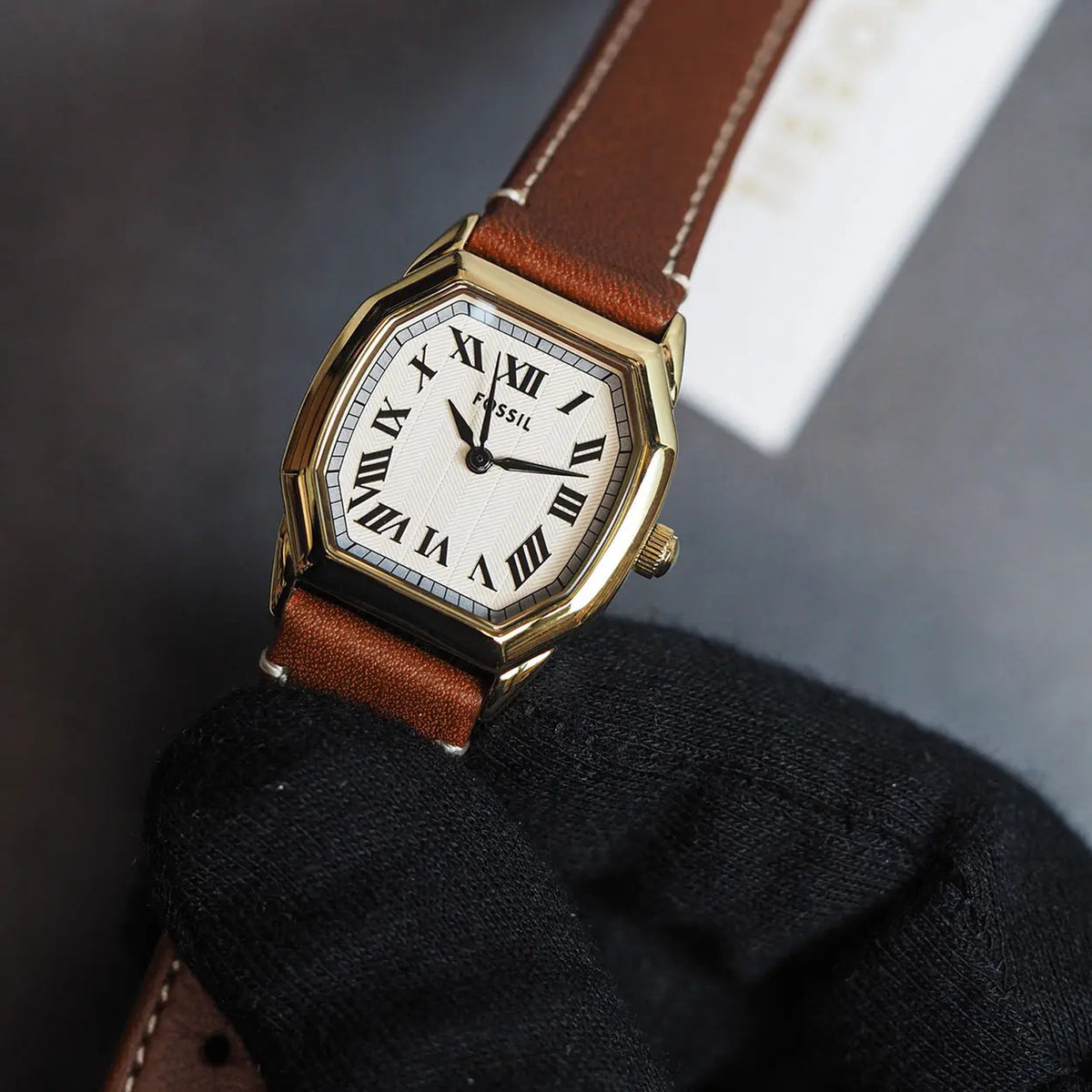 Fossil Harlow ES5364 with a white dial, black Roman numeral hour markers, gold-tone case, signed crown, and brown leather strap.