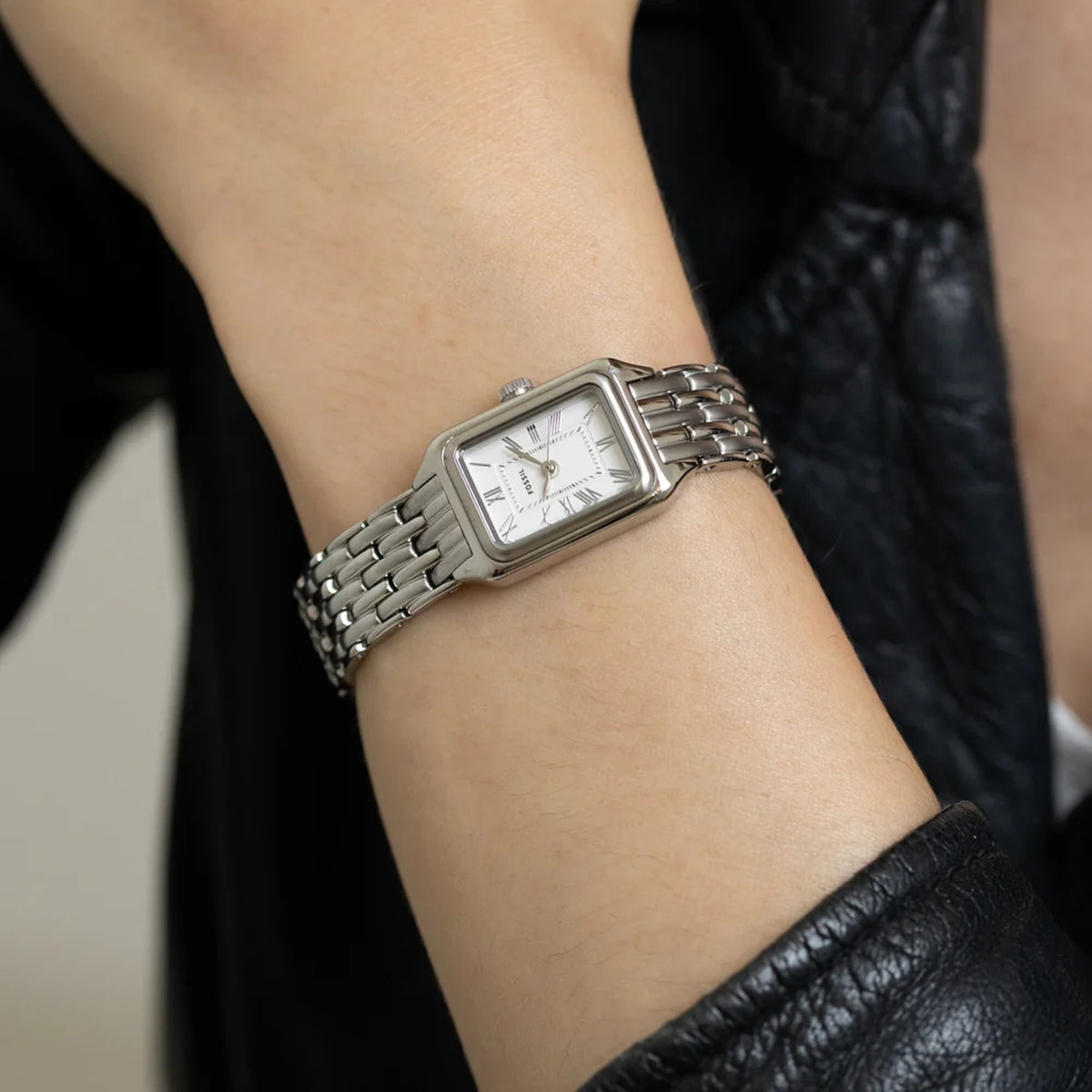 Fossil Raquel Mini ES5469 with a white dial, Roman numeral hour markers, rectangular silver-tone case, and matching silver-tone bracelet worn on the wrist.