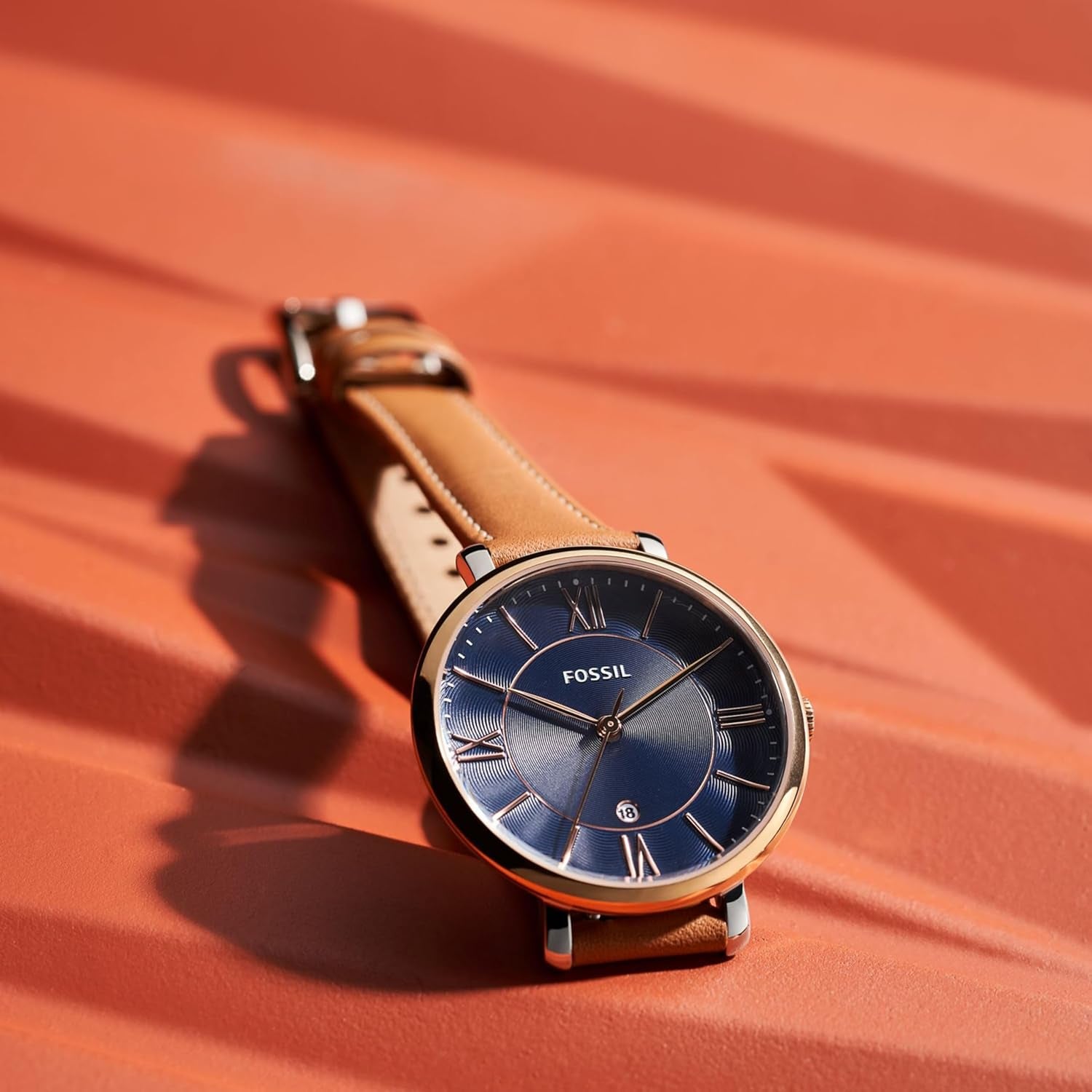 Reloj Fossil para hombre con esfera azul, caja redonda de acero y correa de piel marrón en vista frontal sobre fondo liso.