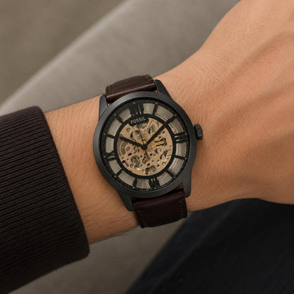 Fossil Townsman ME3098 worn on the wrist with skeleton dial, black stainless steel case, automatic movement, black hour markers, and brown leather strap.