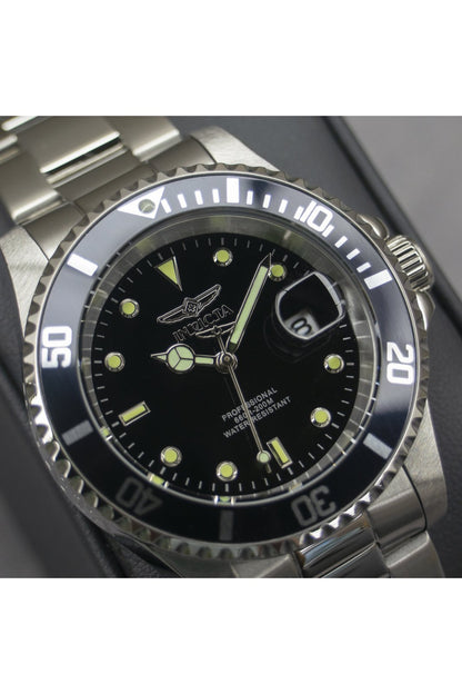 Reloj Invicta analógico de acero con esfera negra y lupa de fecha mostrado en un primer plano detallado.