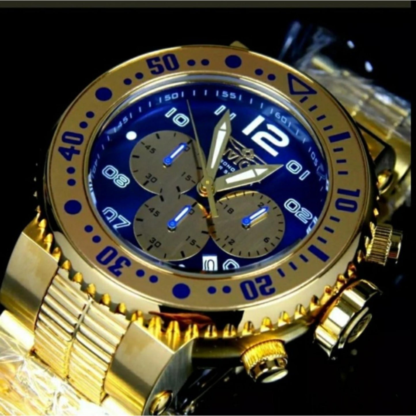 Invicta Pro Diver 25077 chronograph dive watch with blue dial, gold-tone subdials, oversized gold-tone bezel and stainless steel bracelet shown in macro angled view.
