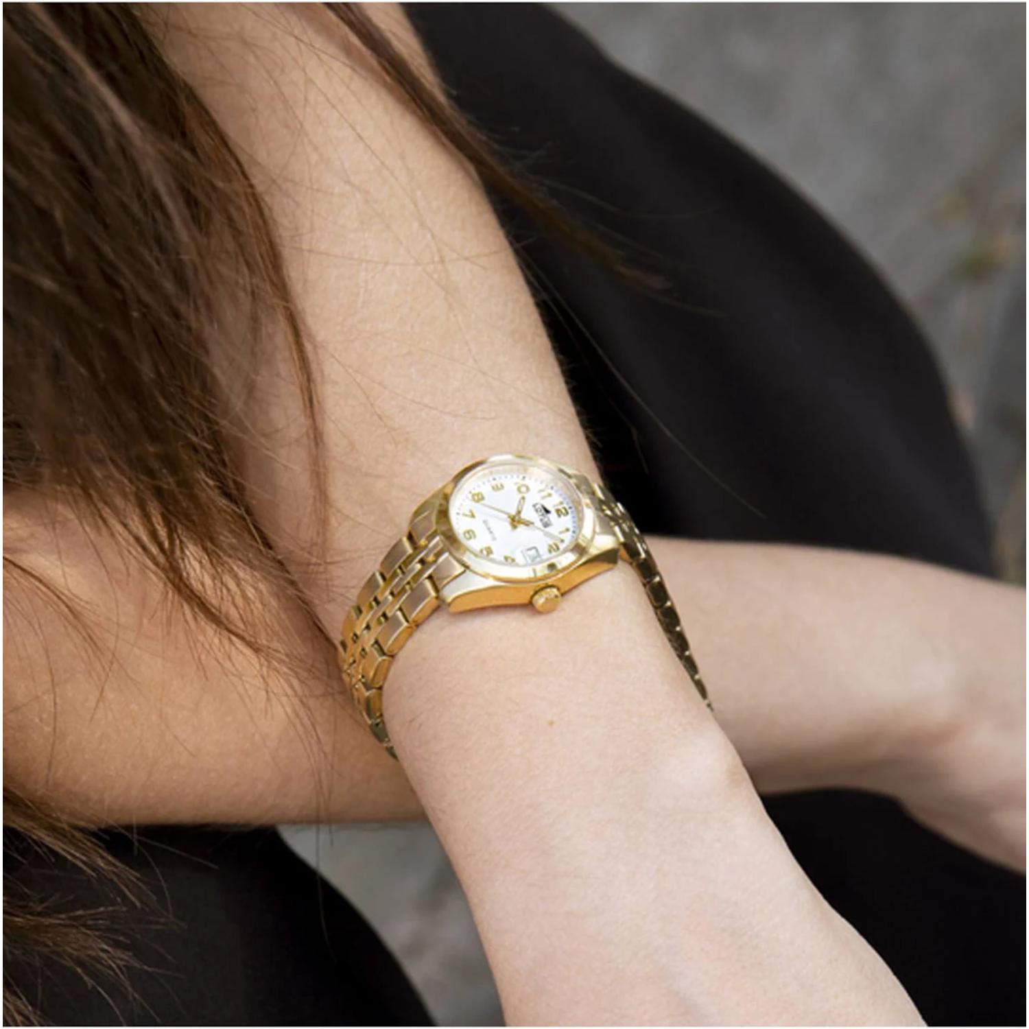 Reloj Lotus 18993/1 de mujer en acero dorado, visto en la muñeca, con esfera blanca y brazalete metálico dorado sobre vestido negro