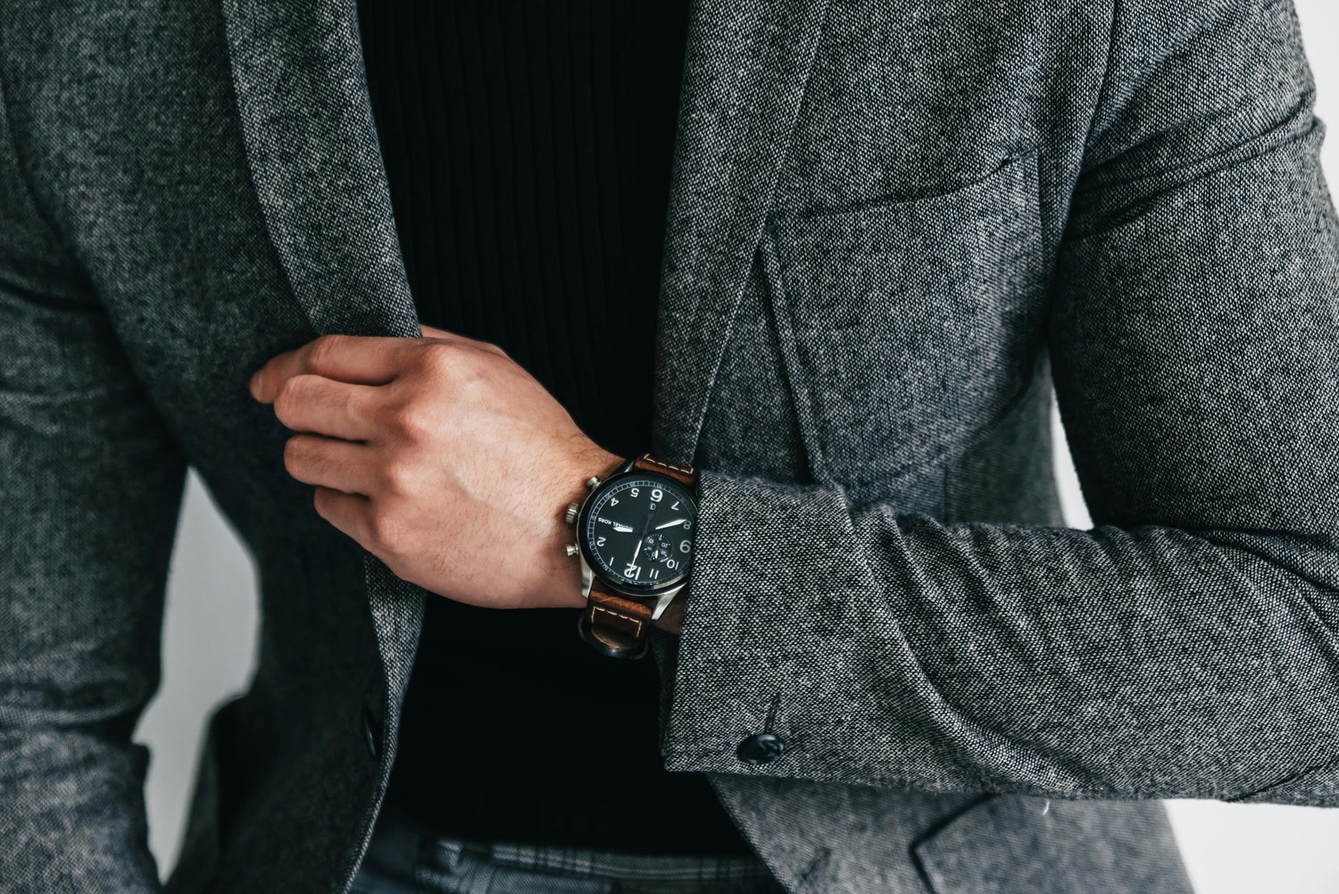 Mens watch with black dial, chronograph style subdials and brown leather strap worn with stainless steel case and classic design