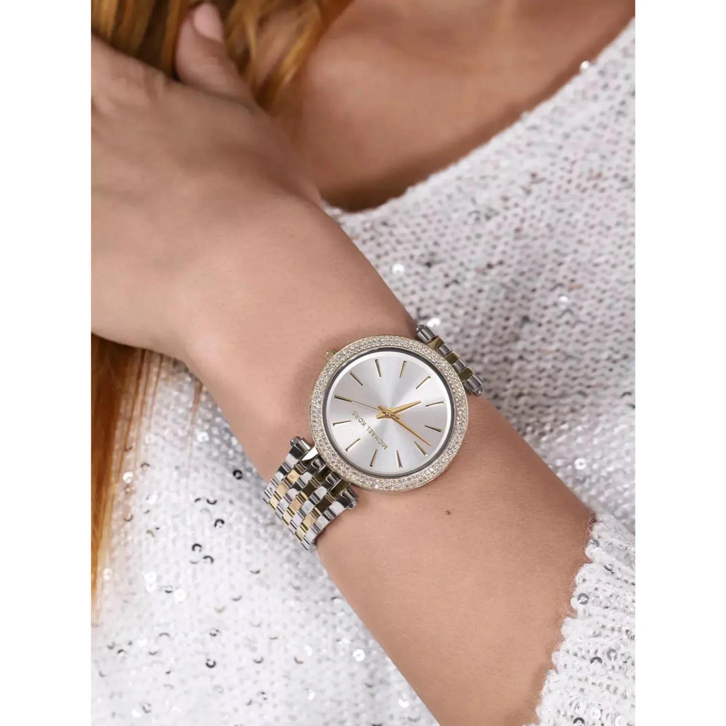 Michael Kors Darci MK3215 women’s watch worn on wrist with white sunray dial, crystal-set bezel and two-tone stainless steel bracelet with gold-tone center links.