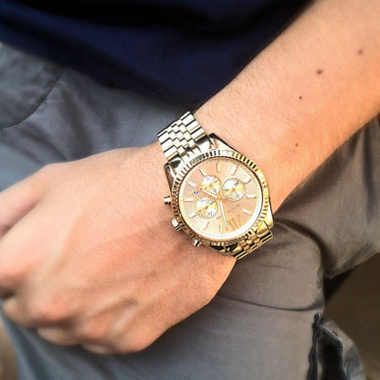 Michael Kors Lexington MK8281 gold-tone chronograph watch worn on wrist with fluted bezel, champagne dial and stainless steel jubilee-style bracelet.