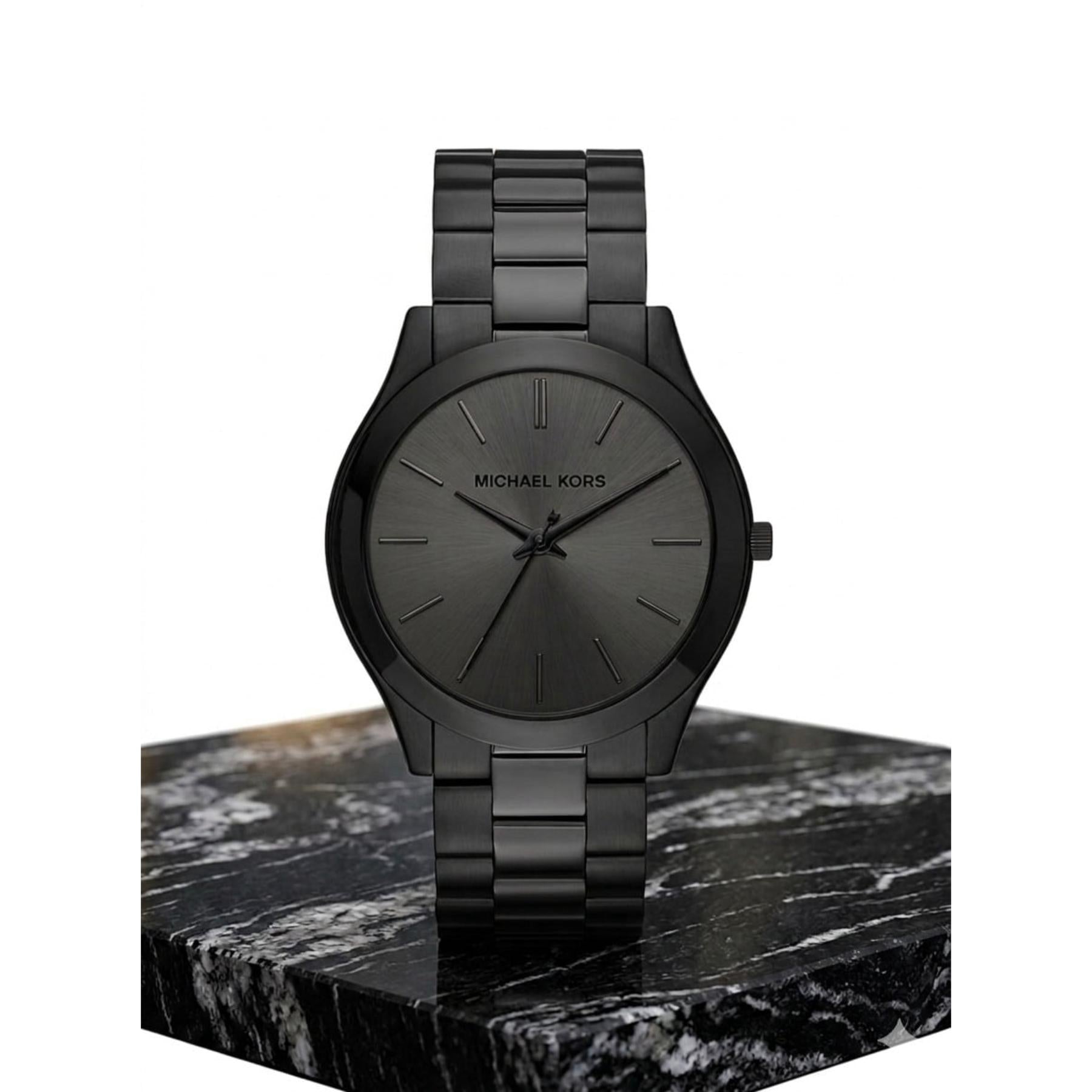 Michael Kors Slim Runway MK8507 with black sunray dial, matte black stainless steel bracelet and minimalist case displayed on marble stand.