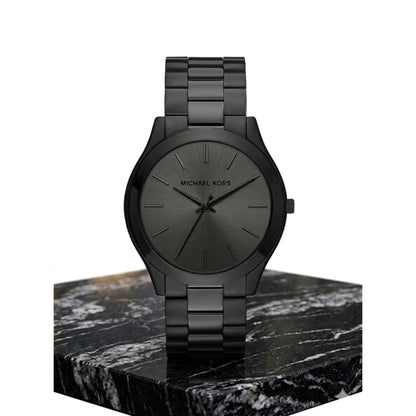 Michael Kors Slim Runway MK8507 with black sunray dial, matte black stainless steel bracelet and minimalist case displayed on marble stand.