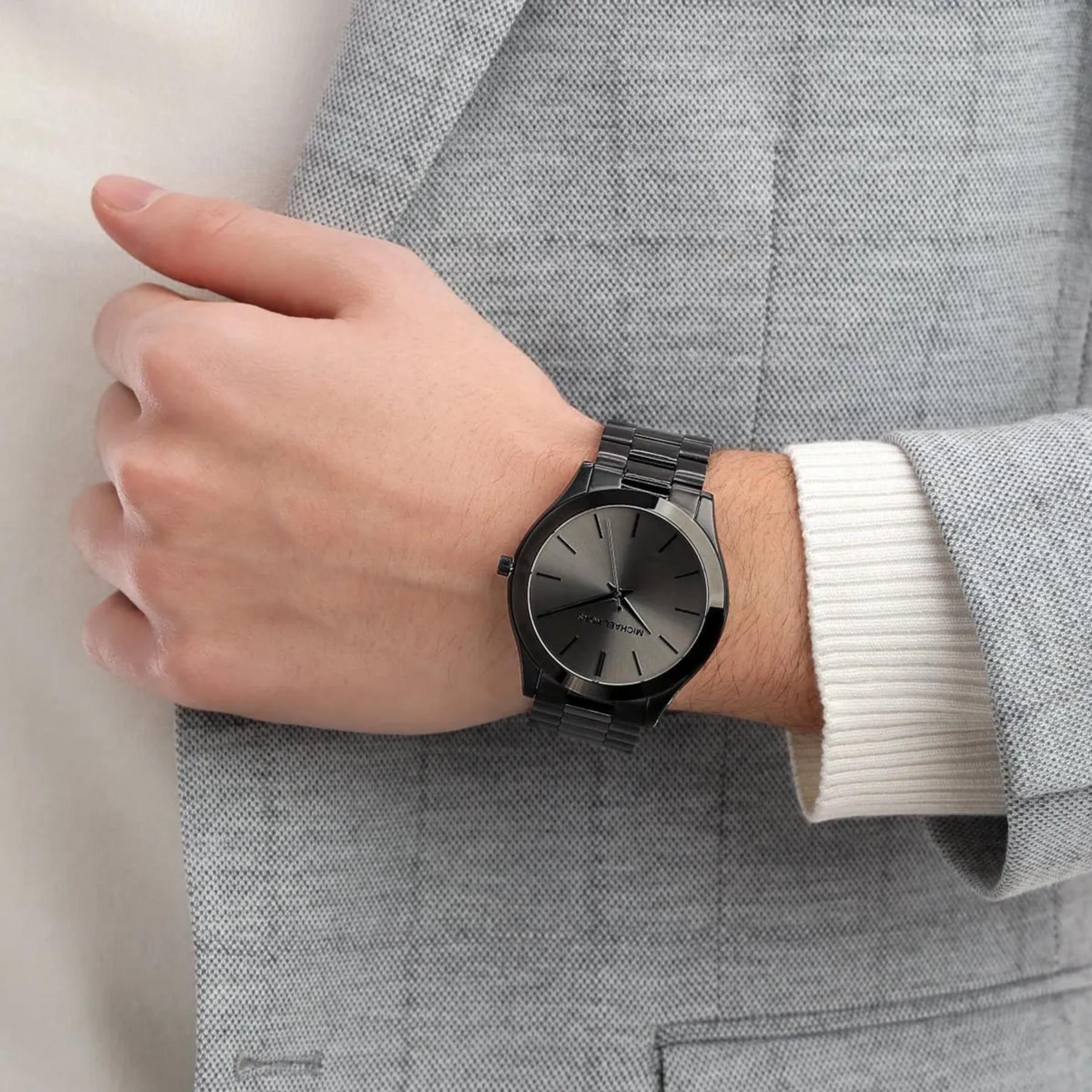 Michael Kors Slim Runway MK8507 black stainless steel watch worn on wrist with minimalist black dial and polished link bracelet.