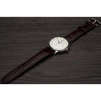 Orient Bambino Small Seconds RA-AP0002S10B automatic dress watch with white dial and brown crocodile-pattern leather strap displayed on a dark wooden surface.