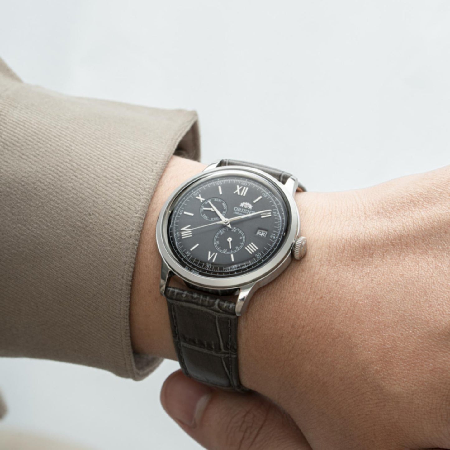 Orient Bambino Version 8 RA-AK0704N10B automatic dress watch worn on wrist with gray dial, Roman numeral markers and dark crocodile-pattern leather strap.