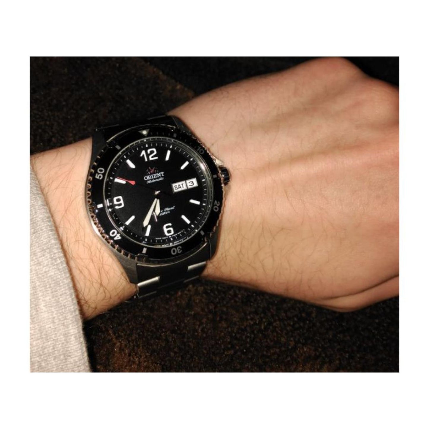 Orient Mako II FAA02001B9 automatic dive watch with black dial, black rotating bezel, and stainless steel bracelet worn on the wrist in a dark setting.