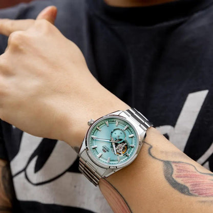 Orient RA-AR0009L automatic dress watch with light blue open-heart dial and stainless steel bracelet worn on the wrist in a casual lifestyle setting.