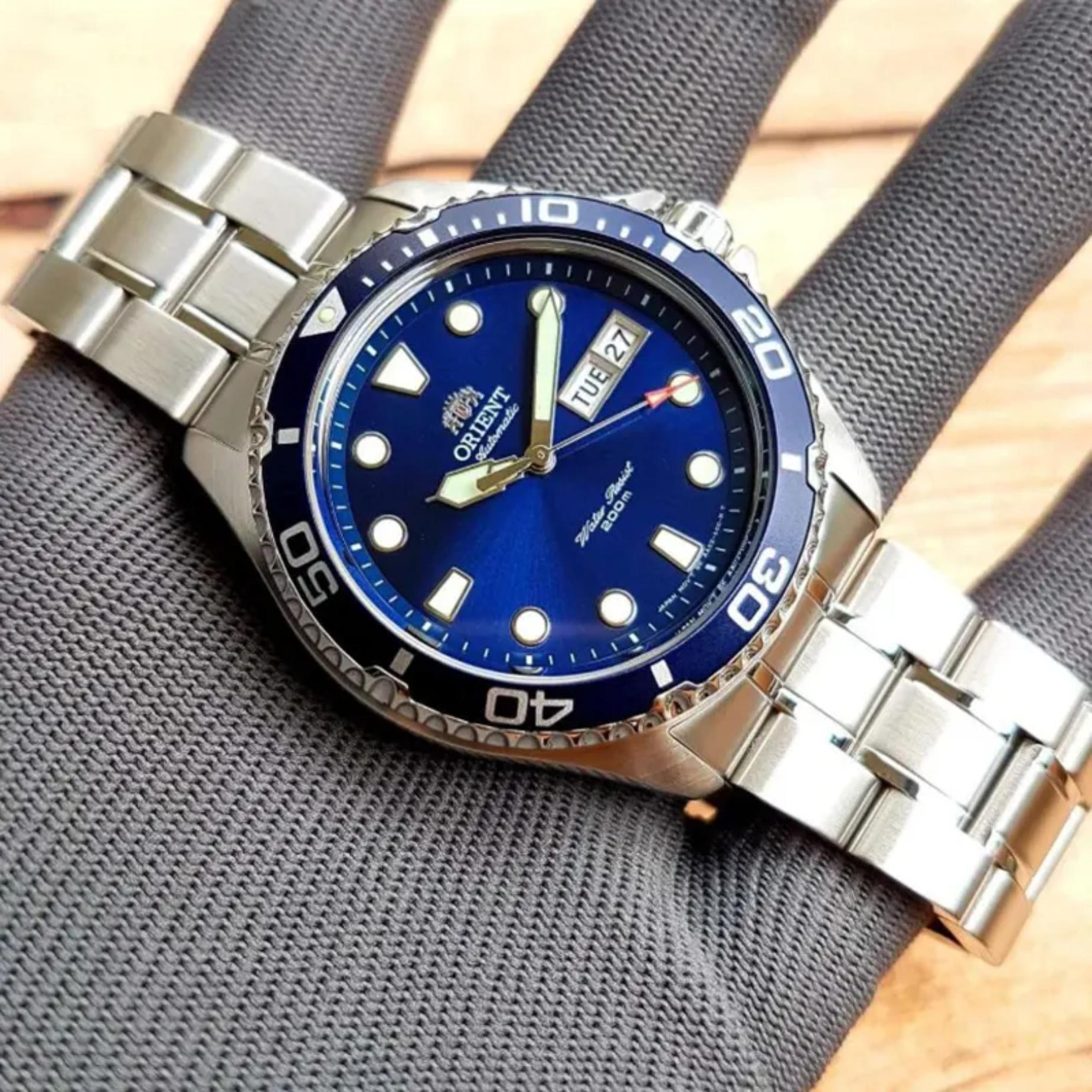 Orient Ray II FAA02005D9 automatic diver watch with blue dial, blue rotating bezel, and stainless steel bracelet displayed on a textured fabric surface.